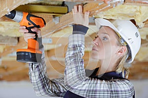 woman drilling wood plank ceiling