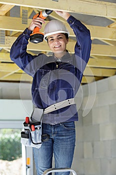 woman drilling wood plank house