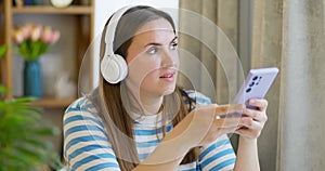 Woman drink a cup of tea and listening to music with headphones in the lounge