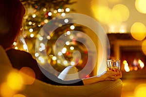 Woman with a drink by a fireplace on Christmas