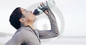 Woman, drink and water at beach for sports break, energy and workout performance. Thirsty athlete, bottle and nutrition