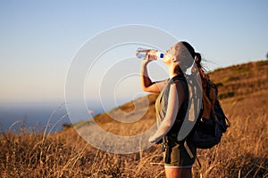 Woman, drink water and hiking outdoor for fitness or travel, thirst and hydration with exploring nature. Backpacking