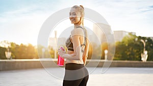 Woman drink water red bottle after morning workout city background