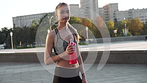 Woman drink water red bottle after morning workout city background