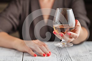 Woman drinking alcohol on dark background. Focus on wine glass