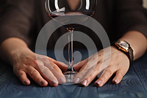 Woman drinking alcohol on dark background. Focus on wine glass