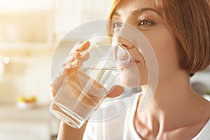 Woman drinking clean water from glass in kitchen