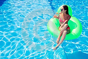 Woman drinking cocktail on air mattress