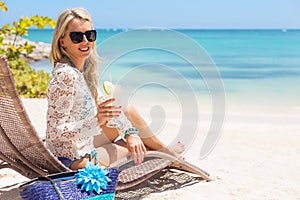 Woman drinking cocktail and relaxing in chair on the beach