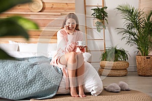 Woman drinking coffee in bedroom with plants. Home design ideas