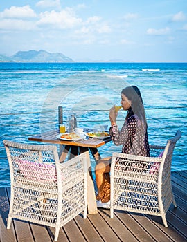 woman drinking coffee at a Breakfast table with a view over the ocean La Digue Seychelles