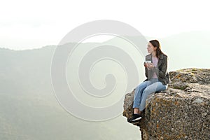 Woman drinking coffee contemplating views from cliff