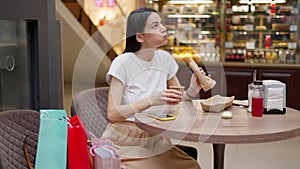 Woman drinking coffee and having lunch in cafe at shopping mall