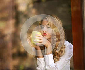 Woman drinking coffee indoors, enjoying the aroma of beverage