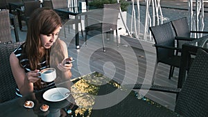 Woman drinking coffee and looking at smartphone