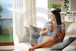 Woman drinking coffee in a luxury home looking outdoor