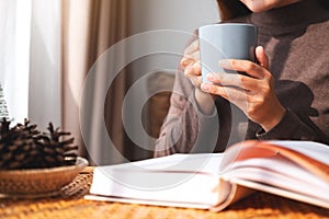 A woman drinking coffee while reading book at home