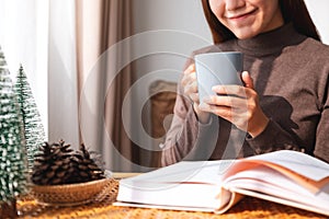 A woman drinking coffee while reading book at home