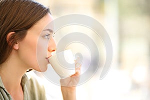 Woman drinking coffee sipping from cup in a bar