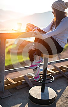 Woman drinking coffee in sun sitting outdoor in sunshine light enjoying her morning coffee