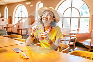 Woman drinking coffee or tea from paper cup in cafe