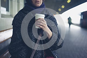 Woman drinking coffee at train station