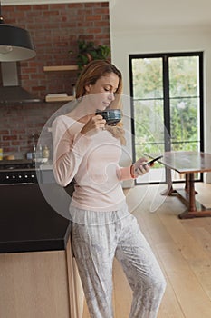 Woman drinking coffee while using mobile phone