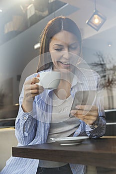 Woman drinking coffee and using a smart phone