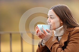 Woman drinking coffee in winter in a balcony