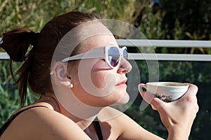 Woman Drinking A Cup Of Coffee Outdoors In The Sun