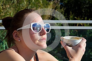 Woman Drinking A Cup Of Coffee Outdoors In The Sun