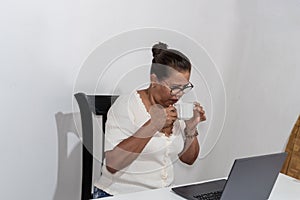 Woman Drinking A Cup Of Coffee While Using Laptop
