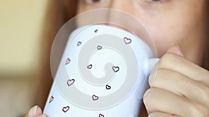 Woman drinking drink close up and holding cup of tea or coffe in hands