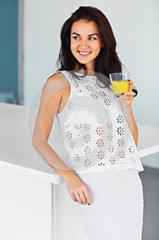 Woman drinking fresh orange juice in the kitchen. Happiness, wel