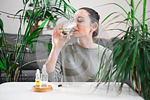 Woman drinking glass with Chlorophyll water, antioxidant beverage. Healthy lifestyle