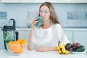 Woman drinking green spirulina in a white kitchen. Detox. Perfect body and calorie. Vegan meal diet at home. Food