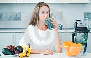 Woman drinking green spirulina in a white kitchen. Detox. Perfect body and calorie. Vegan meal diet at home. Food