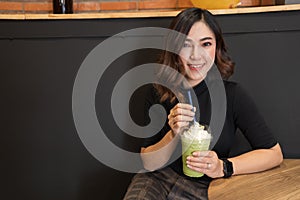 Woman drinking green Tea frappe in cafe photo