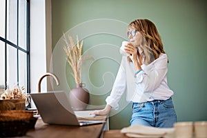 Woman drinking her coffee in the kitchen at the morning
