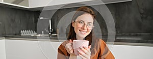 Woman drinking hot coffee at home. Thoughtful young woman drinking a cup of tea while thinking. Pretty girl with sweater