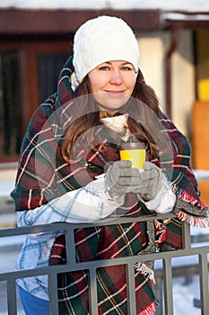 Woman drinking hot coffee from paper cup wrapping with red woollen scarf, wintertime, urban street