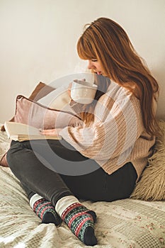 Woman drinking hot tea and reading book. Development and relax