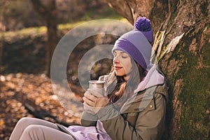 Woman drinking hot tea while taking hiking break
