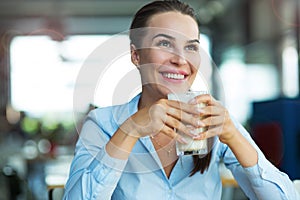 Woman drinking latte macchiato at cafe photo