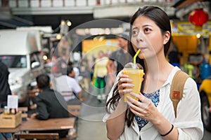 Woman drinking the mango juice in the street