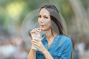 Woman drinking milk shake in the street looking at you