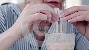 The woman is drinking a milkshake. Woman holding a cocktail glass with two straws