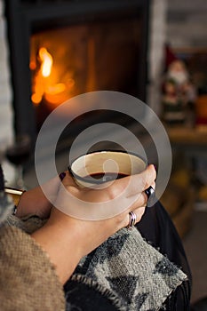 Woman drinking mulled wine by the fireplace