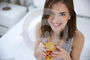 Woman drinking orange juice on the bed