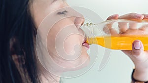 Woman drinking orange juice from a clean bottle. The skin is smooth and beautiful. concept of healthy women, on white background.
